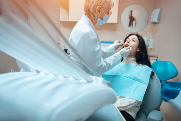 beautiful brunette curly female dentist treat patient in modern clinic