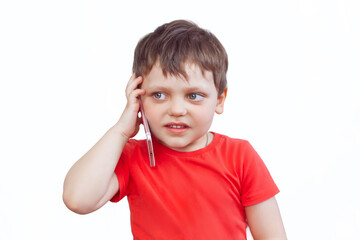 A child in a red t-shirt is talking on the phone. A little boy on a white isolated background. Close-up