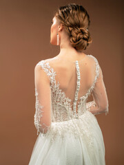 Wedding dress closeup. Rear view with tender french lace, long sleeves, white fabric-covered buttons. Bridal fashion shot in studio on neutral background.