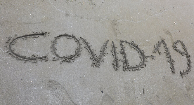 Text Covid-19 on the sand of the beach
