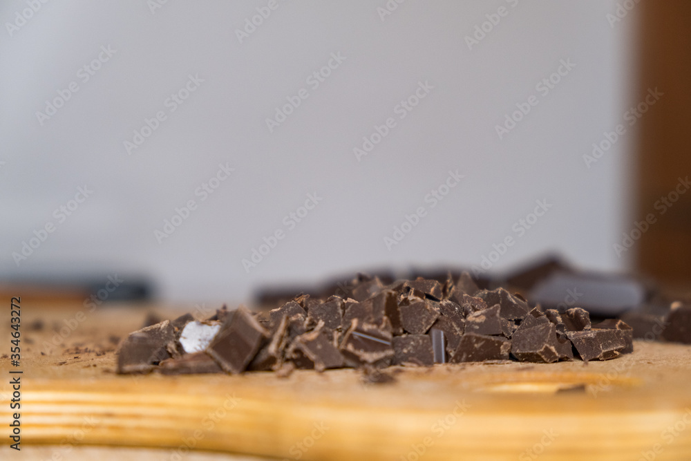 Wall mural selective focus close up shot of chattered dark chocolate pieces on wooden plate.