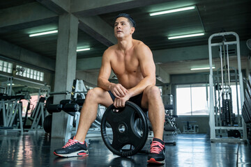 Fototapeta na wymiar Fitness man lifting dumbbell in gym,Athletic man trains with dumbbells.