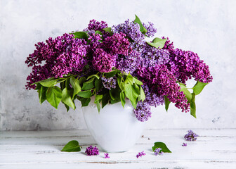 Bouquet of beautiful blooming lilacs in a white vase on a white wooden background. International Women's Day. Mother's day.