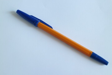 orange pen with a blue cap on a white table