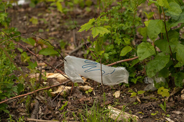 Disposable personal protective equipment discarded in public places (supermarkets parks forests). New type of garbage (masks gloves) during COVID-19 pandemic. Mass environmental pollution by plastic