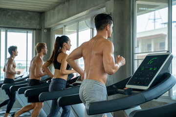 Group of young people using machines workout at gym.