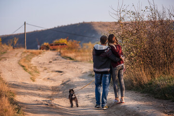 A young couple stands with their backs to the camera and looks to their bright future against a clear blue sky. A happy family travels around the country on their weekends in search of beautiful place