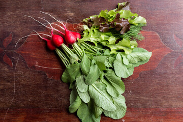 Red radish on a wooden table. Red vegetable with green leaves.