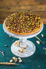 Table with antique cake stand with oriental pistachios dessert. High angle view of turkish sweet dessert of kadayif and pistachios on stand.