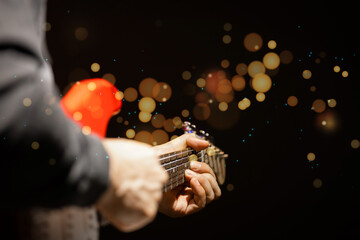male musician playing red electric guitar with twinkling bokeh. music background