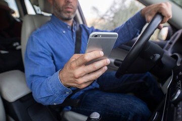 Hombre joven usando el teléfono móvil mientras conduce 