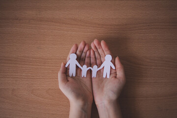 hands holding paper family cutout, family home.