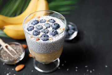 Chia seeds pudding with banana puree and blueberries in glass.