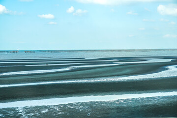 Nature seascape background of sand pattern during low tide under blue sky at Okoshiki beach,...