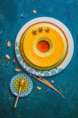 Table with caramel flan dessert next to plate with honey dipper. Top view of caramel pudding with...