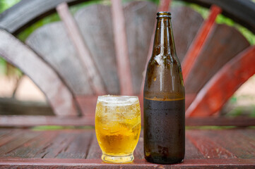 Cold glass of beer and beer bottles on the wooden floor.