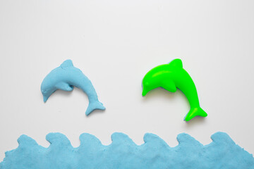 Kinetic sand - modern toy for children development. Form dolphin and blue water.