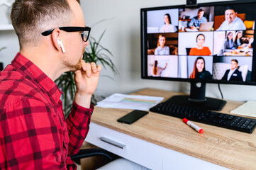 Online video conference. Young man connects via video call with employees, he sits at the office...