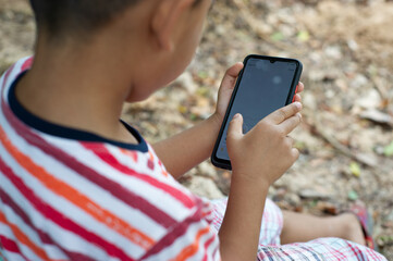 A boy is playing with a mobile phone.