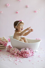 Little girl catches soap bubbles. Children's bathing without tears. The concept of a shampoo that doesn't sting your eyes.