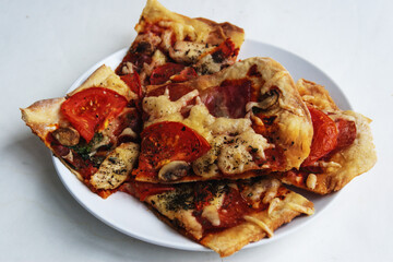 Homemade pizza on a white plate. Candid. View from above.