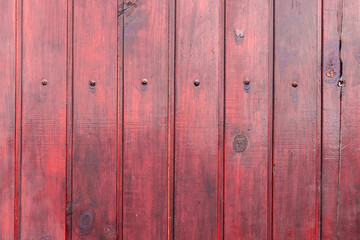Red wooden varnished fence with bolts, background