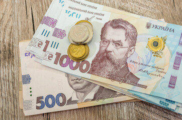 1000 and 500 hryvnia with coins on a wooden background. Close-up. Business concept.