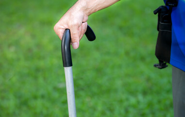 Man hold support stick walking alone on lawn in the courtyard for healthy in his condo residence, Close-up hands of man is walking with walking sticks while walking in the morning exercise. crutches