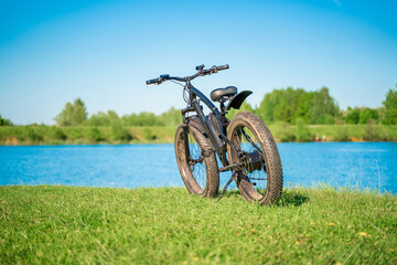 Electric bike with thick wheels near the lake. A pleasant sports hobby that allows you to travel.