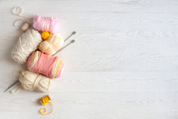Woolen and cotton bright yarn lies in a basket. Glasses lie on a white wooden background.