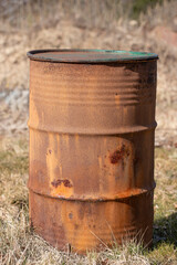 Obraz premium An old rusty barrel standing on dry grass
