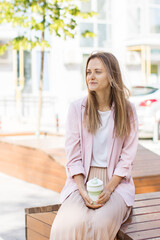 Beautiful young woman with reusable coffee mug on the city street.