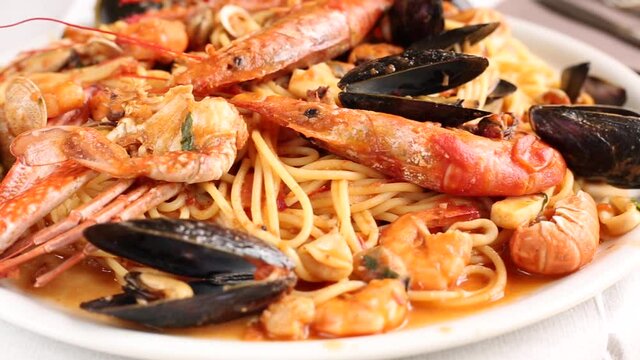 Spaghetti with seafood.Spicy spaghetti with mussels, clams, calamari, shrimp, crab, in tomato sauce close-up on a plate.Famous mediterranean Italian seafood dish -spaghetti allo scoglio