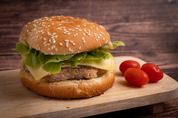 Homemade burger with beef chop, tomato, lettuce and sweet and sour sauce. Serve on a wooden kitchen board. background image, copy space