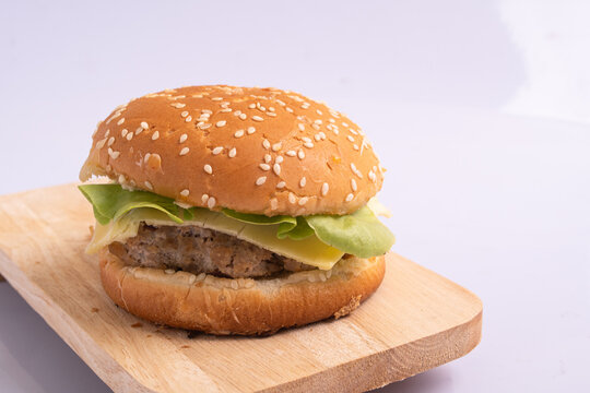Homemade burger with beef chop, tomato, lettuce and sweet and sour sauce. Serve on a wooden kitchen board. background image, copy space