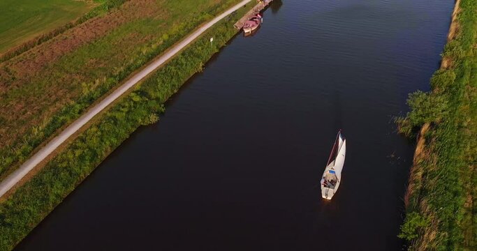 AERIAL: Man sailing on small sailboat in dutch canal in friesland holland top down with drone top down 4K/UHD