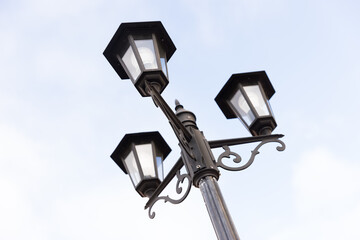 Classic triple streetlight with glass lamps. City lightening.