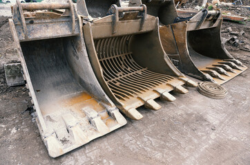 Fototapeta na wymiar Large used excavator shovels stand side by side on a cement floor.