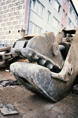 A heavy concrete shear used as excavator attachments lies on the ground on a demolition site..