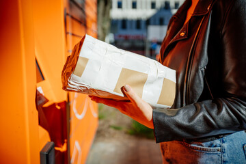 Young women using public parcel machine to sent mail