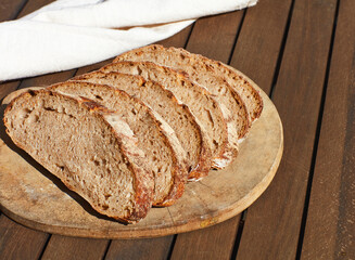Sliced Artisan bread with whole wheat crust on wooden table.
