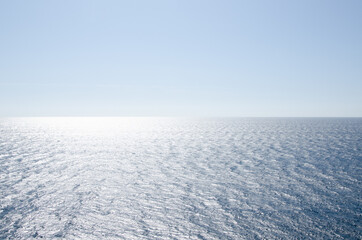 Seascape background of clear sky and vivid blue sea with sunlight reflection on surface