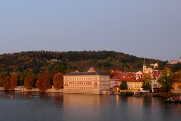 Picturesque Prague embankment in the fall. Forested hill.