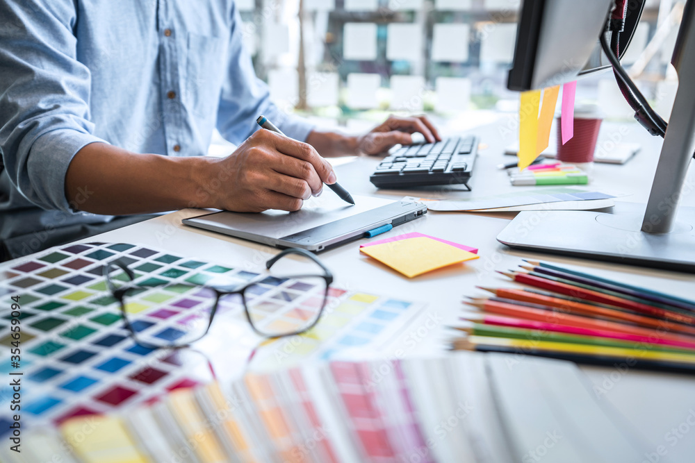 Aufkleber Image of male creative graphic designer working on color selection and drawing on graphics tablet at workplace with work tools and accessories in workspace
