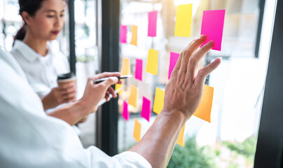 Creative team using post it notes in glass wall to writing strategy