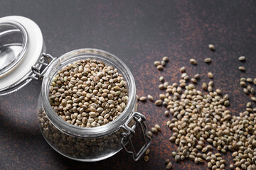Hemp seeds in glass jar on brown. Close up
