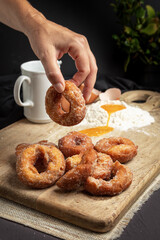 Hand holds a homemade doughnut on a rustic table