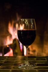 Full wine glass on the table and fireplace background