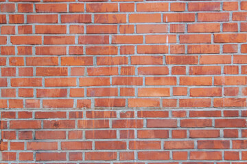 Old red brick wall. Bricks with individual texture with concrete layering .
