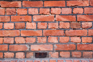 Fototapeta premium Old red brick wall. Bricks with individual texture with concrete layering .